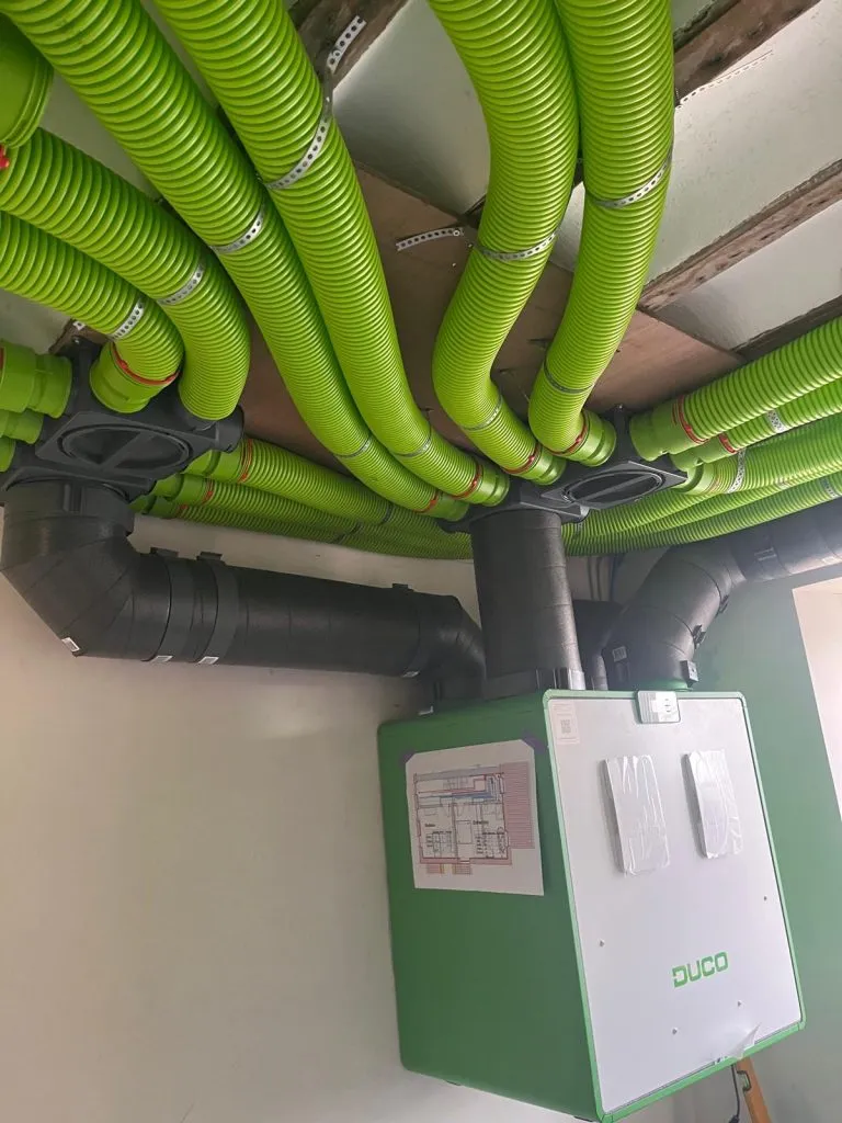 Installation DIY d'un système de ventilation double flux DUCO, avec des conduits verts flexibles et un caisson de ventilation, réalisée par un client.